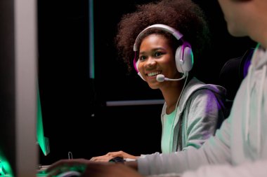 Genç Afrikalı Amerikalı kadın ve Asyalı erkek kulaklık takıyor video oyunu oynuyor ve canlı yayında mikrofon, oyun ve esport ile rekabet veya oyuncu seçimi, eğlence konsepti.