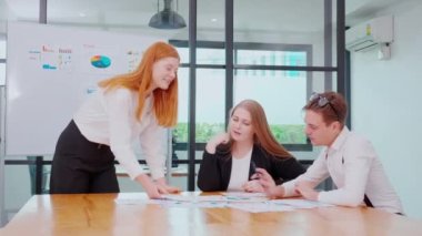 Grup iş adamları finans ve kâr hakkında pazarlama ile buluşurken, iş kadını da planlama ve beyin fırtınası için meslektaşlarıyla birlikte sunum ve grafikleri ve grafikleri beyaz tahtada açıklıyor..