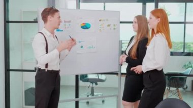 Grup iş adamları finans ve kâr hakkında pazarlama ile buluşurken, iş adamı sunumu ve çizelge ve grafiği partnerle birlikte planlama ve beyin fırtınası için açıklar..