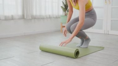 Kafkasyalı genç bir kadın, evde meditasyon hazırlığı ve dinlenme egzersizi için yerde yoga yapıyor, egzersiz yapıyor ve yoga ve sağlık için hobiler geliştiriyor..