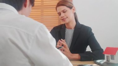 Genç Asyalı müşteri emlakçıyla ev satın alma ve ipotek emlak anlaşması hakkında konuşuyor ve ev ofisinin planlama, finans ve yatırım, iş konseptini anlatıyor..