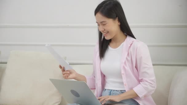 年轻的亚洲女商人在笔记本电脑上工作 在纸上寻找利润的图表和报告 而在家里获得成功 女商人寻找投资和收入 信息数据 — 图库视频影像