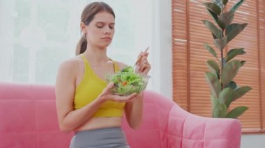 Kafkasyalı genç bir kadın kanepesinde oturmuş elinde sebze salatası tutarken tiksinti ve dışavurumdan tiksiniyor iştahsızlıktan, vejetaryenlikten ve nefretten bıkmış bir kadın hissi beslenme konsepti..
