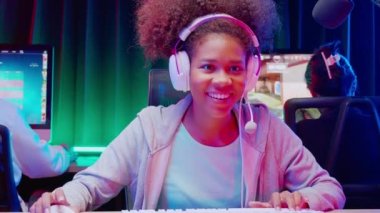 Genç Afro-Amerikan kadın ve takımı kulaklık takarak video oyunu oynuyor ve canlı yayında mikrofon, oyun ve esport ile rekabet veya oyuncu seçimi, yayın ve eğlence kavramı ile çevrimiçi olarak yayınlanıyor..