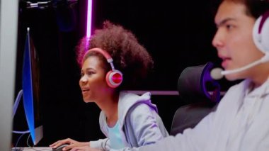 Genç Asyalı erkek ve Afrikalı Amerikalı kadın kulaklık takıyor ve canlı yayında mikrofonla birlikte oynuyorlar, oyun ve esport ya da heyecan verici, eğlence konsepti olan oyuncu bulma oyunu..
