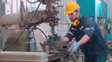 Genç Kafkasyalı mühendis, fabrika endüstrisinde, teknisyen veya işgücü bakım makinelerinde üretimi hazırlamak için torna makinesini çalıştırıyor..