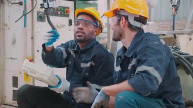 Genç mühendis konuşuyor ve robot silahlanma teknolojisi hakkında konuşuyor partnerle birlikte zeka ve fabrikada el sıkışma, bakım makinesi, uzaktan kumandalı insanlar, endüstriyel konsept.