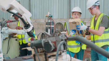 Mühendis erkek ve kadın robot silahları hakkında konuşuyor ve anlatıyor. Teknoloji zekası ve yenilik fabrikada, geliştirme makinesinde, insanlar uzaktan kumandayla makine ve endüstriyel konsept kullanıyorlar..