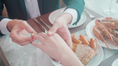 Evlilik ya da nişan için kadının parmağına yüzük takan erkeğin elleri restoran, lüks, aşk ve nişanlı, yıldönümü ve kutlama, sevgi ve bağlılık..