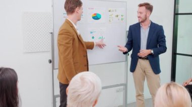Grup iş adamları seminer düzenler ve finans ve kâr üzerine pazarlama ile görüşürken, iş adamları da planlama ve alkışlamayla ilgili meslektaşlarıyla grafikler ve grafikler sunar..