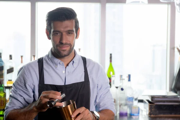 Young caucasian man is bartender holding and shaker for mixing beverage preparation serving with professional at counter, portrait handsome male, barman standing with confident at restaurant.