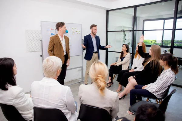 Young caucasian businessman asking opinion and brainstorm of employee while raise hand up for participation together at office, community of business and meeting of leader for presentation project.