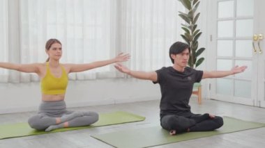 Genç Asyalı erkek ve kadın yoga yapıyor ve rahatlamak için meditasyon yapıyor ve evdeki paspasın üzerinde hayatı dengeliyor, çift oturma ve antrenman yoga egzersizi, sağlık ve spor konsepti..