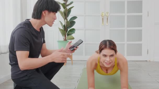 年轻女子用体式踏板进行锻炼 而亚洲男子教练则决定在家里迎接挑战 全心全意地为健康 体育理念进行锻炼和训练 — 图库视频影像