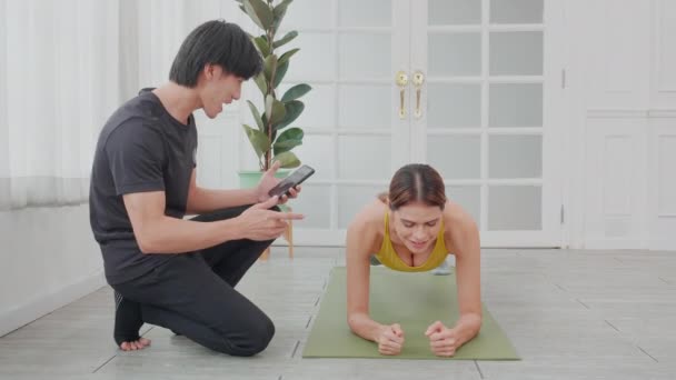 年轻女子用体式踏板进行锻炼 而亚洲男子教练则决定在家里迎接挑战 全心全意地为健康 体育理念进行锻炼和训练 — 图库视频影像