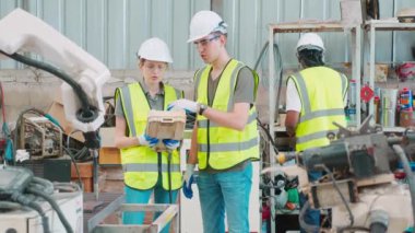 Mühendis erkek ve kadın robot silahları hakkında konuşuyor ve anlatıyor. Teknoloji zekası ve yenilik fabrikada, geliştirme makinesinde, insanlar uzaktan kumandayla makine ve endüstriyel konsept kullanıyorlar..