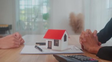 Closeup hands of young realtor woman real estate giving house model to hands customer man while agreement and contract achievement and approval and handshake at office, business concept.