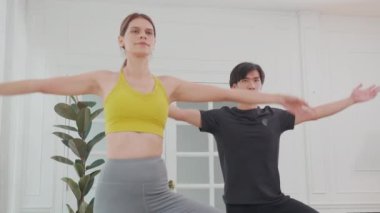 Genç bir kadın ve Asyalı erkek yoga yapıyor. Kasları esnek, bacakları ve elleri evde. Vücut bakımı için yoga, vücut esnekliği, spor ve sağlık konsepti ile rehabilitasyon yapıyor..