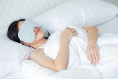 Güzel Asyalı genç bir kadın örtülü göz takıyor ve yatak odasında başı yastıkta uyuyor rahatlık ve mutlulukla, rahatlık ve rahatlık için boş vakti olan bir kız, yaşam tarzı konsepti..