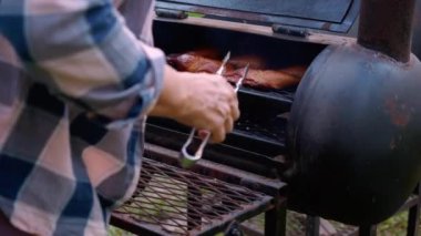 Senior woman grilling chicken meat for preparing eat in camping, elderly doing activity recreation and leisure picnic while roasting meat in weekend, travel trip in holiday, party in vacations.