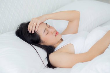 Genç Asyalı kadın yatak odasında baş ağrısı, mutsuz kadın yorgunluğu ve baş ağrısı, endişe ve rahatsızlık, baş dönmesi ve düzensizlik, tıbbi ve sağlık konsepti..