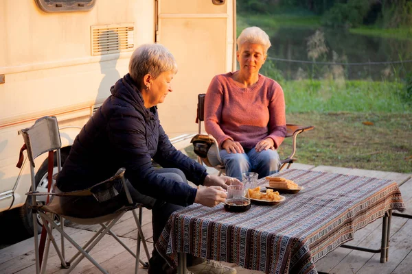 Two senior woman talking and leisure in camping, elderly doing activity recreation and leisure picnic while breakfast together in morning in weekend, travel trip in holiday, party in vacations.