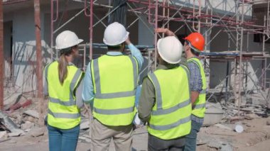 Bir grup müteahhit ve mimar ustabaşıyla birlikte proje planlama projesini işçilere ve proje, inşaat alanı, geliştirme ve yapıya bakmaları için planlama sahasından bahsediyorlar..