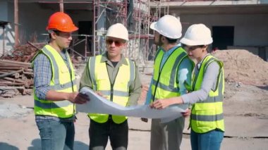Bir grup müteahhit ve mimar ustabaşıyla birlikte proje planlama projesini işçilere ve proje, inşaat alanı, geliştirme ve yapıya bakmaları için planlama sahasından bahsediyorlar..