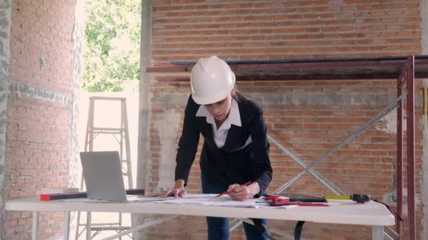 ラップトップを探している若い白人建築家の女性と設計図を描く作業机の上に家を計画するための エンジニアの思考と建設のための青写真をスケッチ 産業概念 — ストック動画