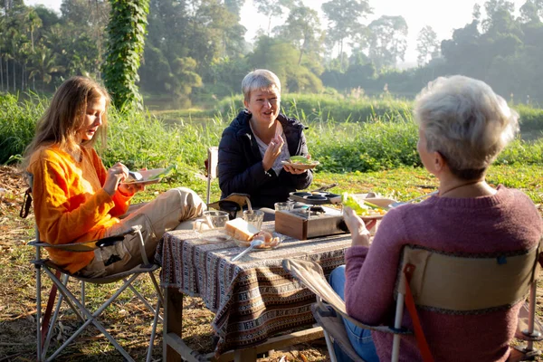 Two senior woman and teenager talking and leisure in camping, activity recreation and leisure picnic while breakfast together in morning in weekend, travel trip in holiday, party in vacations.