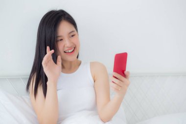 Genç Asyalı bir kadın, internet üzerinden arkadaşlarıyla video konferans için akıllı telefon kullanıyor. İş kadını, sosyal ağla görüşmek için telefon görüşmesi yapıyor. Akıllı telefon, iş ve iletişim kavramı..