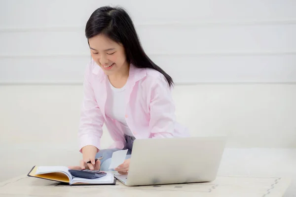 Young asian woman calculating finance household with calculator on desk at home, girl checking bill for saving and planning expenses, debt and loan, tax and accounting, business and financial concept.