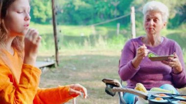 Two senior woman and teenager talking and leisure in camping, activity recreation and leisure picnic while breakfast together in morning in weekend, travel trip in holiday, party in vacations.