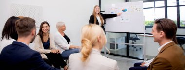 Grup iş adamları semineri düzenler ve finans ve kâr pazarlama ile görüşürken, iş kadını da planlama ve beyin fırtınası için meslektaşlarıyla grafikler ve grafikler sunar..