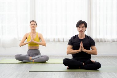 Yoga ve meditasyon yapan genç erkek ve kadın evdeki paspasın üzerinde hayatı dengelemek için meditasyon yapıyorlar. Kadın ve erkek oturma ve egzersiz yoga, sağlık ve spor konsepti..