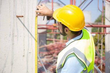 Engineer young man using tape measure for check and examining length of structure with professional at construction site, architect inspection and improvement infrastructure, industry concept.