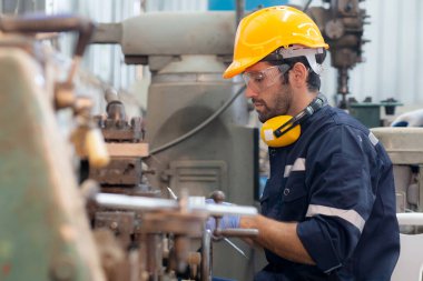 Genç Kafkasyalı mühendis, fabrika endüstrisinde, teknisyen veya işgücü bakım makinelerinde üretimi hazırlamak için torna makinesini çalıştırıyor..
