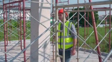 İşçi, mimar veya müteahhit olmak üzere inşaat alanında çalışan işçi ve anket ile telsiz komutası kullanan genç mühendis kontrol ve planlama yapı evi, ustabaşı veya denetçisi için telsizle konuşur..