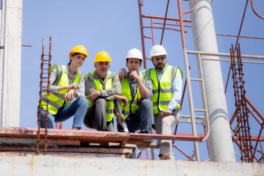 Bir grup müteahhit ve mimar ustabaşıyla birlikte proje planlama projesini işçilere ve proje, inşaat alanı, geliştirme ve yapıya bakmaları için planlama sahasından bahsediyorlar..