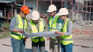 Bir grup müteahhit ve mimar ustabaşıyla birlikte proje planlama projesini işçilere ve proje, inşaat alanı, geliştirme ve yapıya bakmaları için planlama sahasından bahsediyorlar..