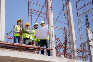 Bir grup müteahhit ve mimar ustabaşıyla birlikte proje planlama projesini işçilere ve proje, inşaat alanı, geliştirme ve yapıya bakmaları için planlama sahasından bahsediyorlar..