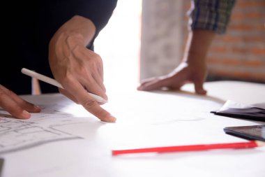 Closeup hands young caucasian architect woman looking laptop and working drawing blueprint for planning building house, engineer thinking and sketching blueprint for construction, industry concept.