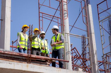 Bir grup müteahhit ve mimar ustabaşıyla birlikte proje planlama projesini işçilere ve proje, inşaat alanı, geliştirme ve yapıya bakmaları için planlama sahasından bahsediyorlar..