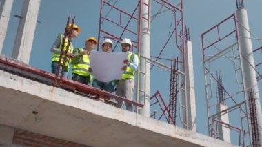 Bir grup müteahhit ve mimar ustabaşıyla birlikte proje planlama projesini işçilere ve proje, inşaat alanı, geliştirme ve yapıya bakmaları için planlama sahasından bahsediyorlar..