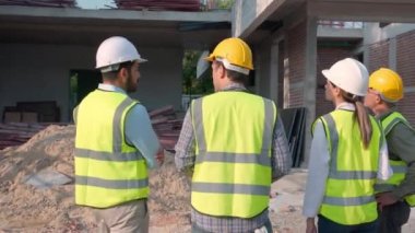 Grup mühendisi toplantısı. Lider inşaat alanında çalışan işçiyle planlama ve araştırma yaparken müteahhit ve mimar inşaat sahası ve teftişi, endüstriyel konsepti tartışacak..