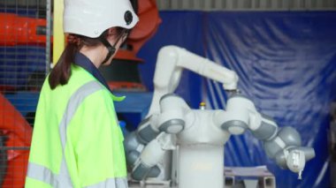 Genç mühendis kadın robotları kontrol ediyor ve sunuyor. Teknoloji zekası ve icadı fabrika endüstrisinde. Teknisyen robotların otomatik, müfettiş ve endüstri konseptini gösteriyor..