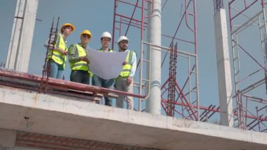Bir grup müteahhit ve mimar ustabaşıyla birlikte proje planlama projesini işçilere ve proje, inşaat alanı, geliştirme ve yapıya bakmaları için planlama sahasından bahsediyorlar..