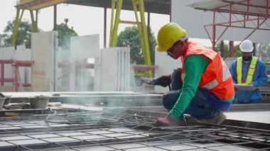 Endüstriyel fabrikayı, kaynakçıyı ya da işçiyi incelerken makineli kaynak demiri kullanan genç Asyalı işçi, yönetici kontrol ederken kaynak makinesi kullanıyor, endüstri kavramı.