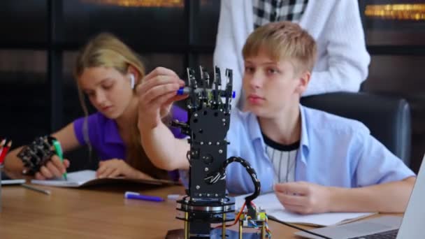白人の2人の10代の学生は 学校で一緒に教室でロボットアームを学ぶ 教師と認識とコントローラ研究ロボットAiを使用して男の子と女の子 教育と開発の概念 — ストック動画