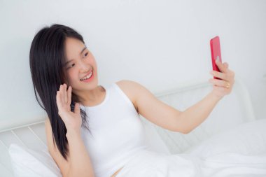 Genç Asyalı bir kadın, internet üzerinden arkadaşlarıyla video konferans için akıllı telefon kullanıyor. İş kadını, sosyal ağla görüşmek için telefon görüşmesi yapıyor. Akıllı telefon, iş ve iletişim kavramı..